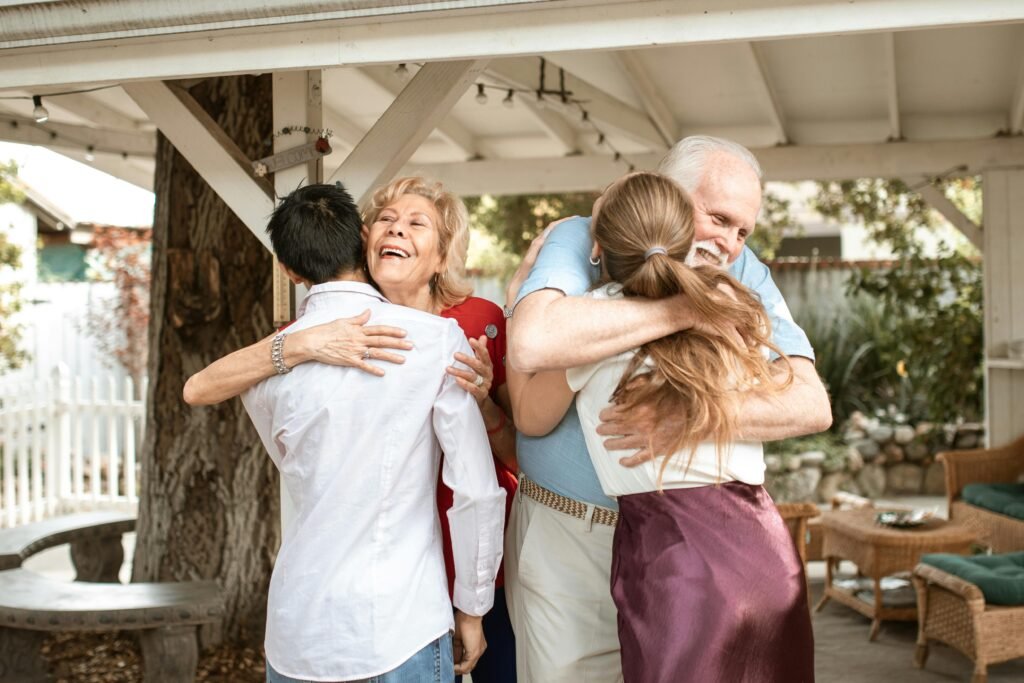 A joyful family reunion outdoors with warm hugs and smiles under a wooden pergola.